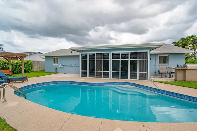 a view of pool with lawn chairs and plants