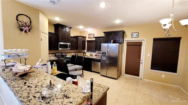 a kitchen with stainless steel appliances kitchen island granite countertop a refrigerator and a stove top oven