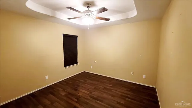 an empty room with a ceiling fan and wooden floor
