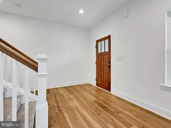 a view of an empty room with wooden floor and stairs