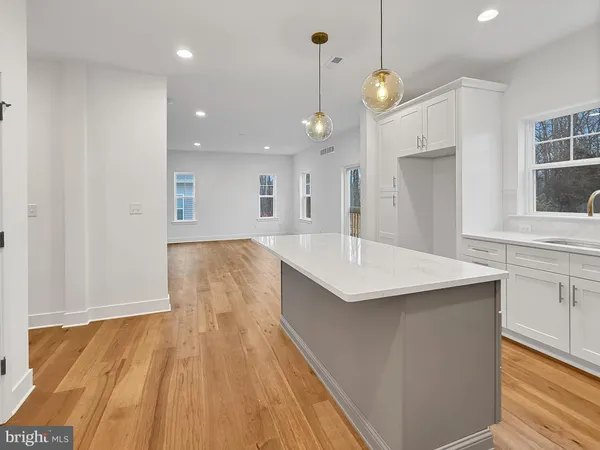 a kitchen with kitchen island a sink dishwasher and a stove with wooden floor