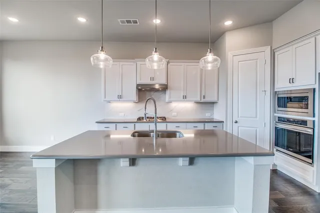 a large kitchen with stainless steel appliances a large counter top a stove and a sink