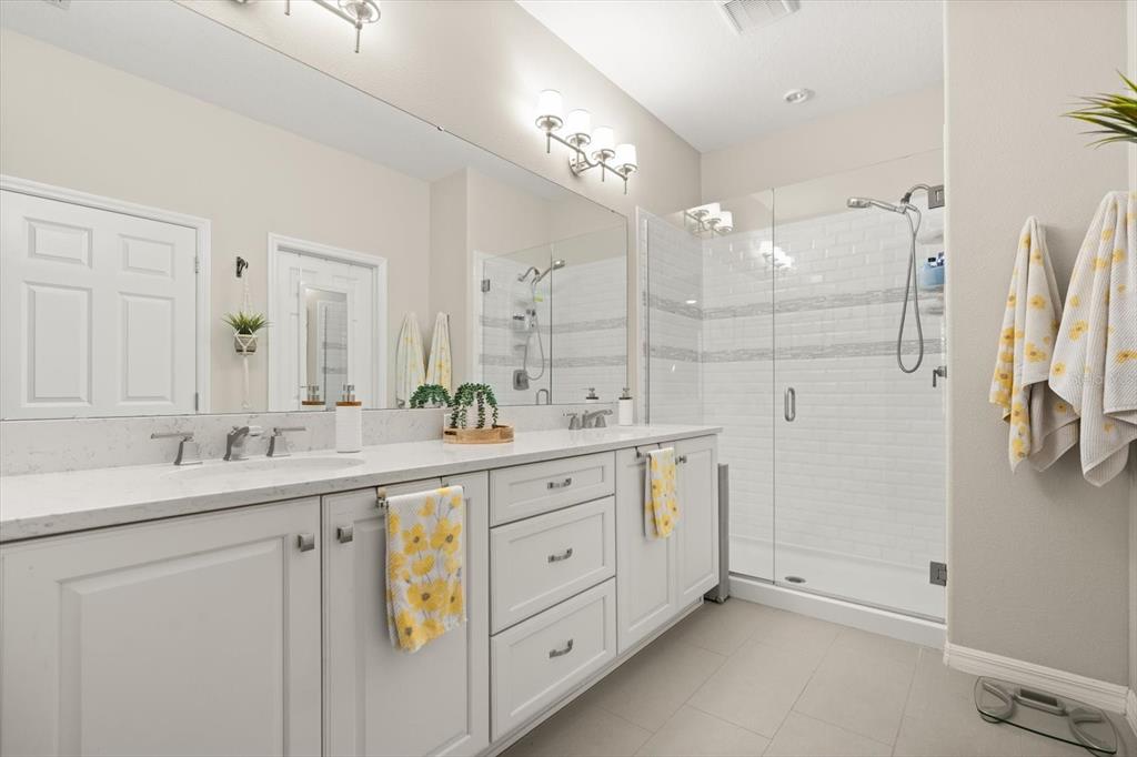 100 Silver Maple Road Groveland, FL 34736 - Photo 14 of 54 a spacious bathroom with a double vanity sink a mirror and a shower