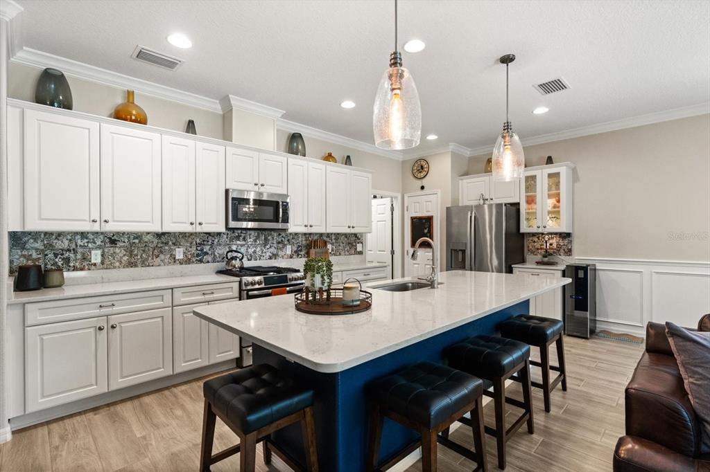 100 Silver Maple Road Groveland, FL 34736 - Photo 3 of 54 a kitchen with stainless steel appliances kitchen island granite countertop a table chairs stove and refrigerator