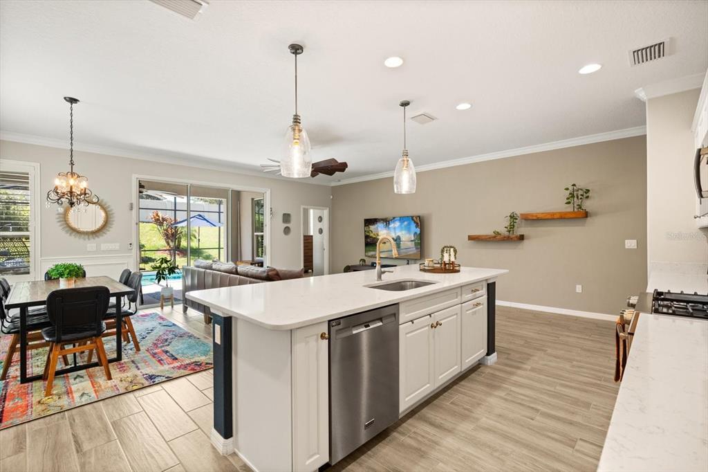 100 Silver Maple Road Groveland, FL 34736 - Photo 6 of 54 a large kitchen with stainless steel appliances kitchen island granite countertop a sink a stove and a wooden floors