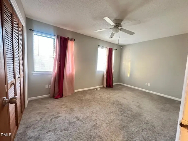 an empty room with windows and fan
