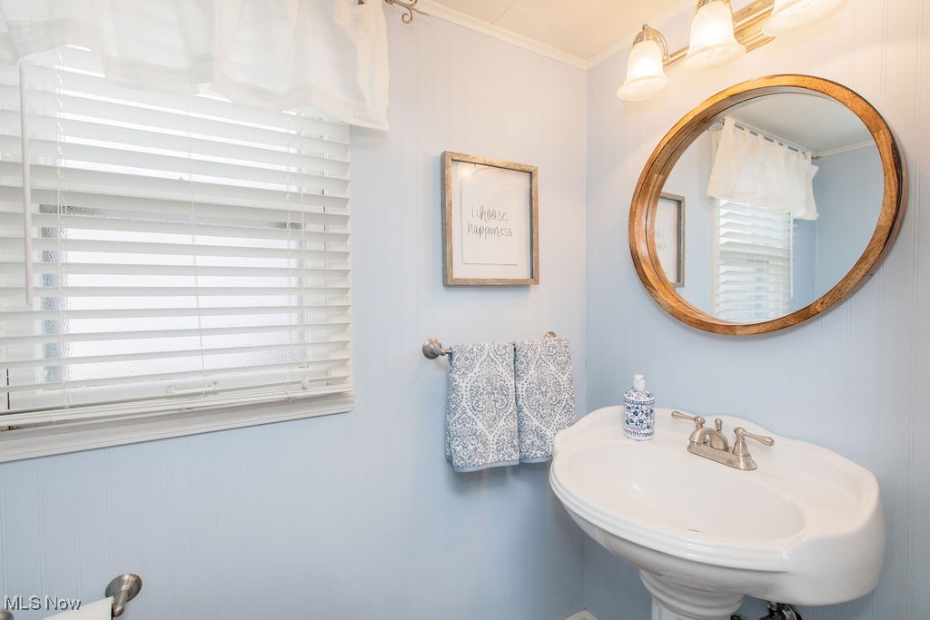 1528 Oakmount Road South Euclid, OH 44121 - Photo 13 of 24 Powder room with ceramic tile flooring, updated white pedestal sink and toilet, brushed nickel fixtures, a striking circular wood trimmed mirror, and overhead lighting.