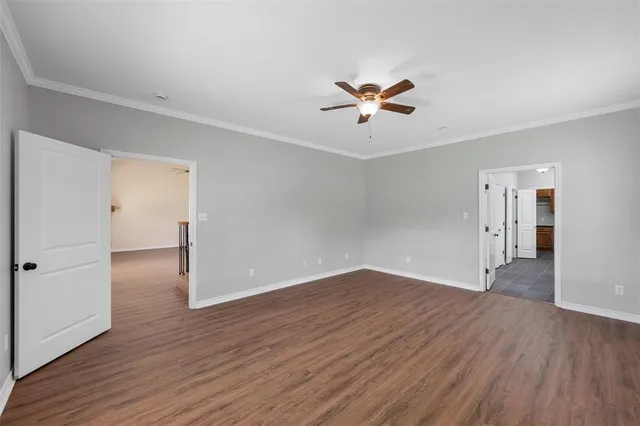 an empty room with wooden floor and ceiling fan