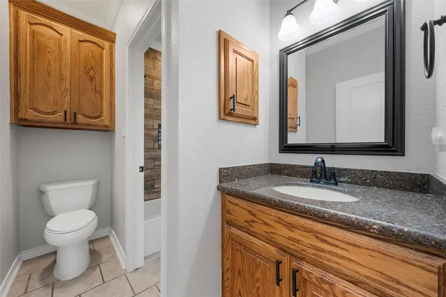 a bathroom with a granite countertop toilet sink and mirror