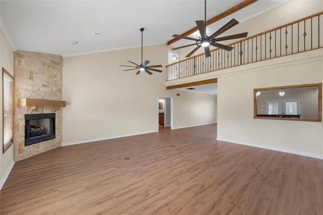 a view of empty room with wooden floor fireplace and a window