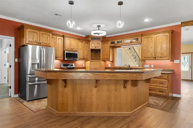 a kitchen with stainless steel appliances granite countertop a refrigerator a stove and a sink with wooden floor