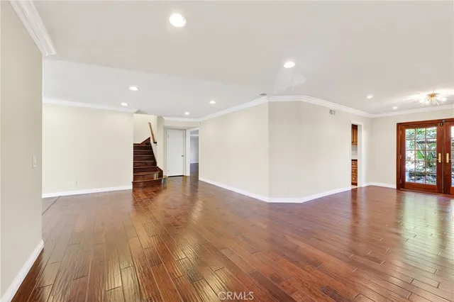 a view of an empty room with wooden floor and windows