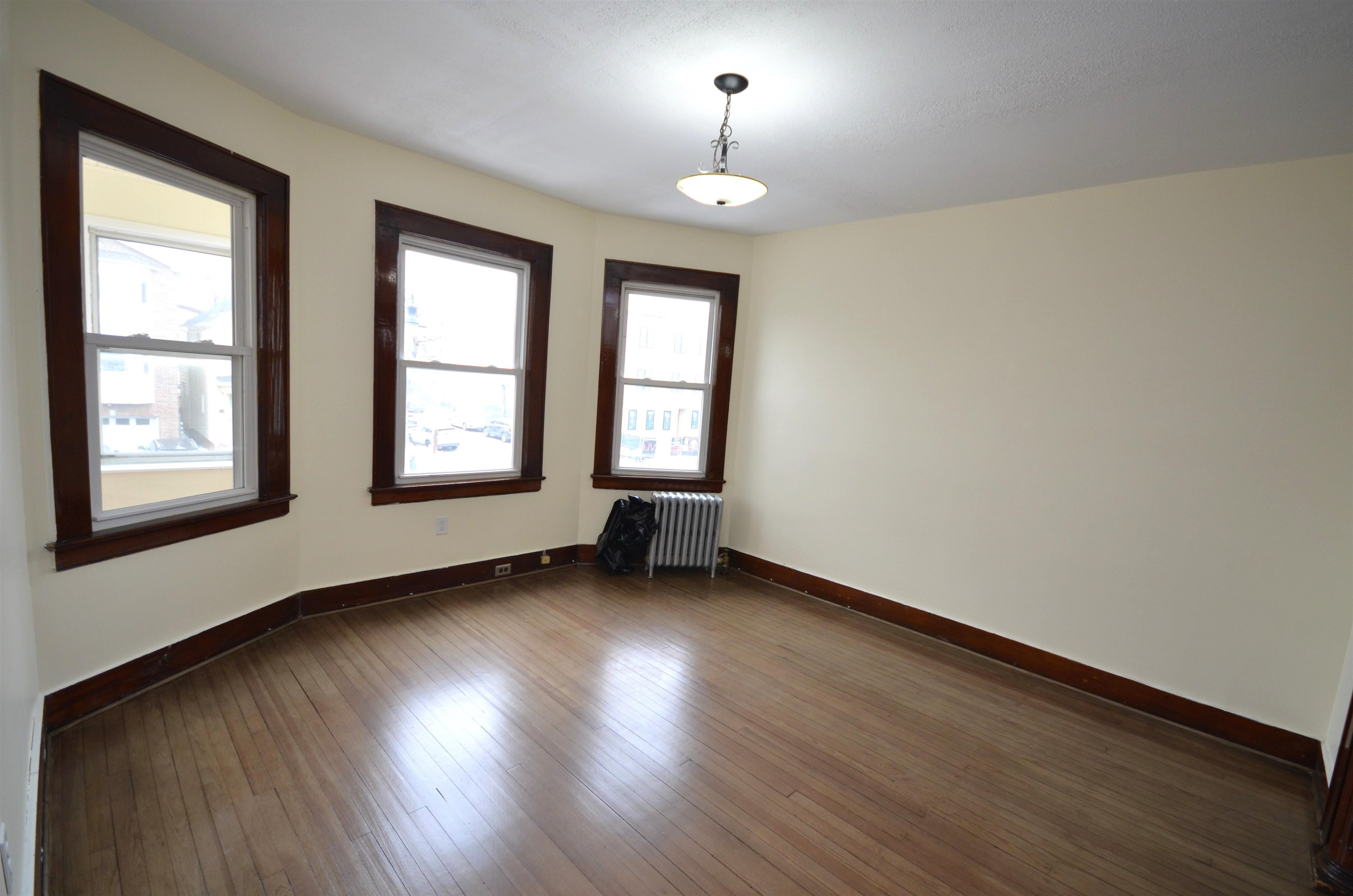 413 Davis Avenue, Unit 2 Harrison, NJ 07029 - Photo 3 of 8 a view of an empty room with wooden floor and a window