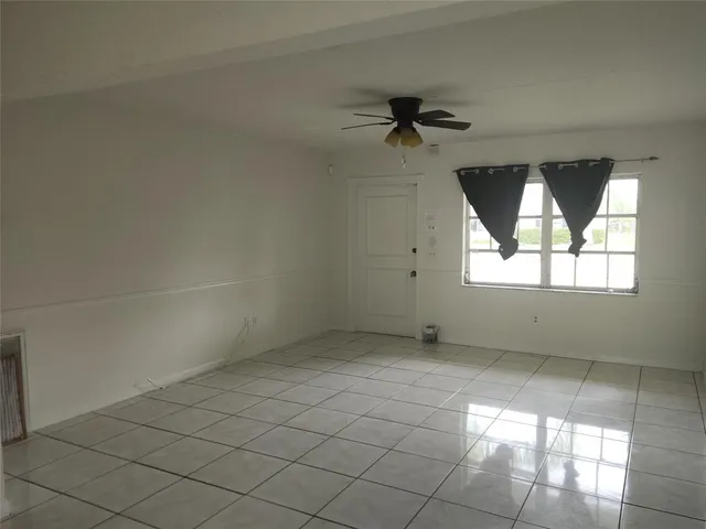 an empty room with windows and fan
