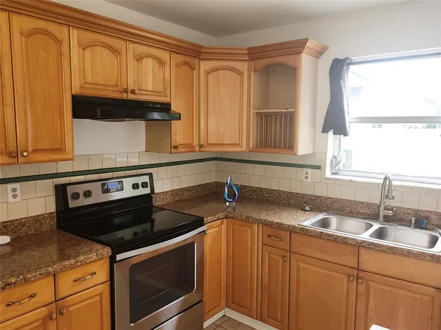 a kitchen with granite countertop a sink stove and cabinets