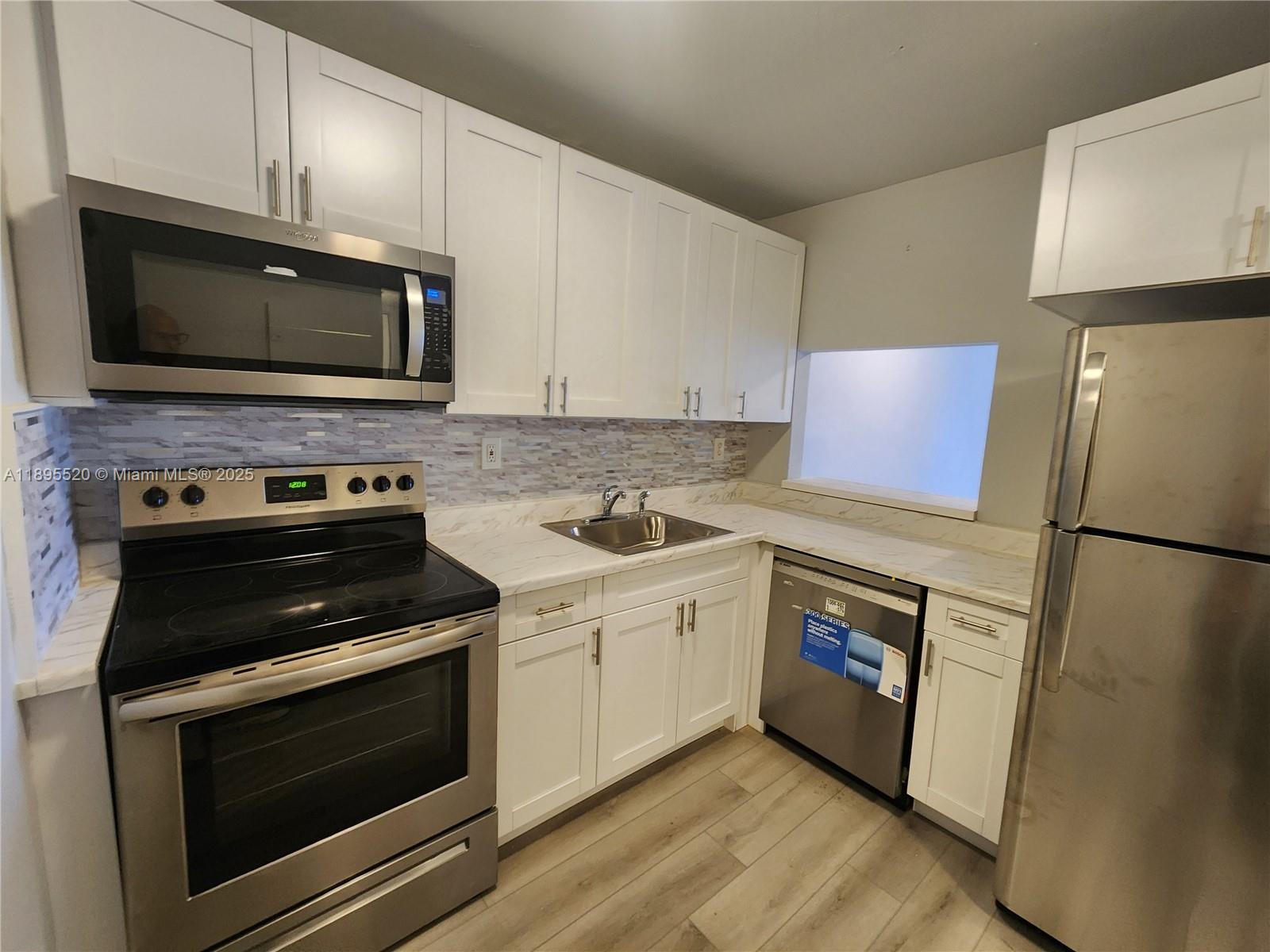 11309 Southwest 200th Street, Unit 303C Miami, FL 33157 - Photo 2 of 21 a kitchen with a stove and a microwave