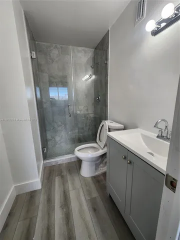 a bathroom with a sink a toilet a mirror and shower
