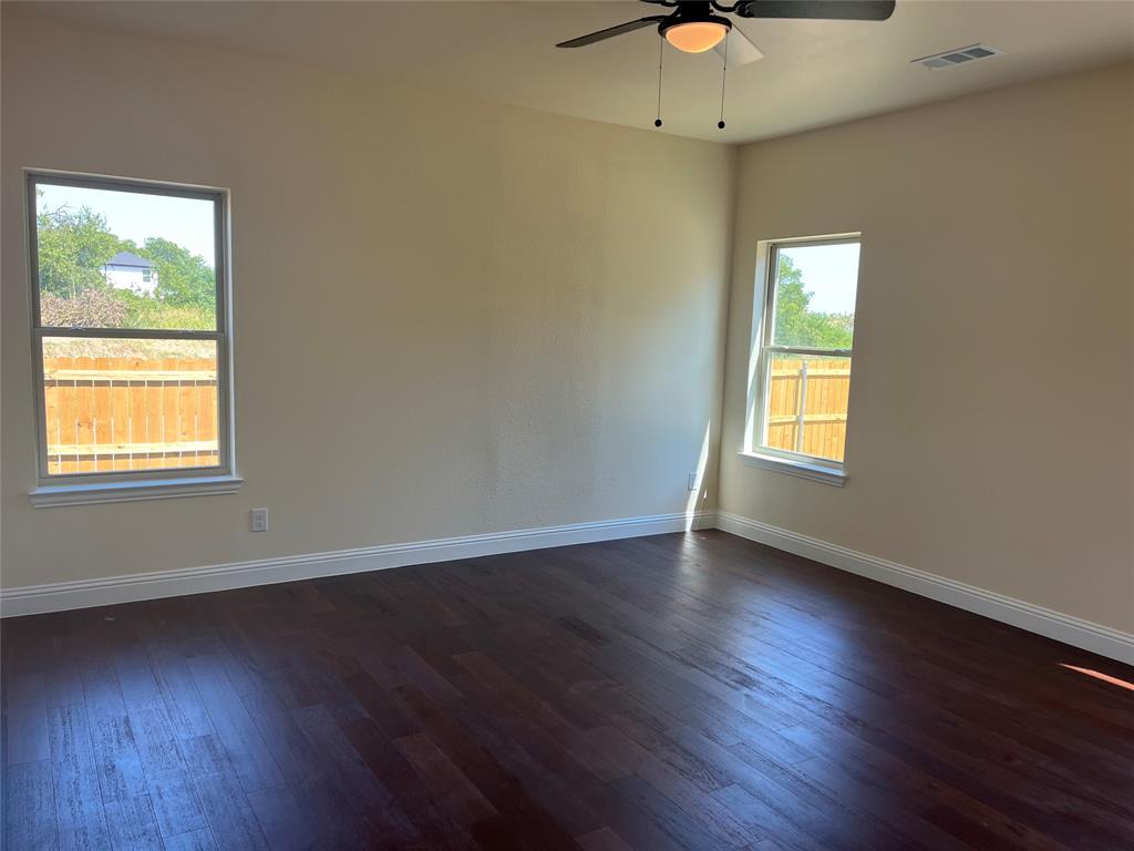 5332 Booker T Street Fort Worth, TX 76105 - Photo 7 of 18 an empty room with wooden floor chandelier fan and windows