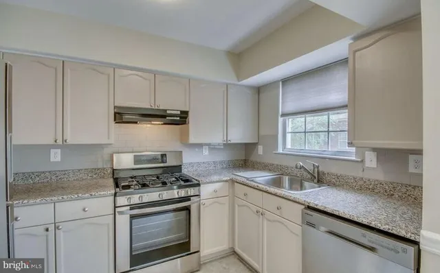 a kitchen with stainless steel appliances granite countertop a sink stove and cabinets