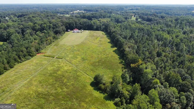 an aerial view of residential house with outdoor space and trees all around