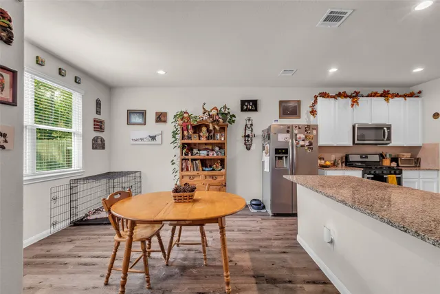 a kitchen with stainless steel appliances a dining table chairs and a refrigerator