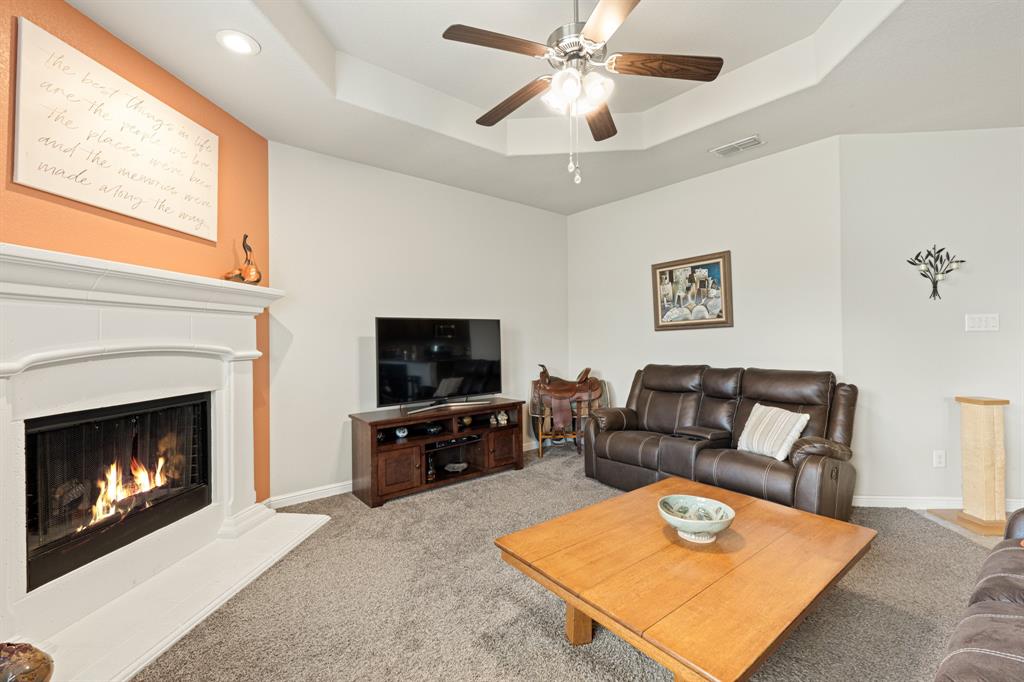 916 Falcon Road Argyle, TX 76226 - Photo 23 of 37 Carpeted living room with a tray ceiling and ceiling fan