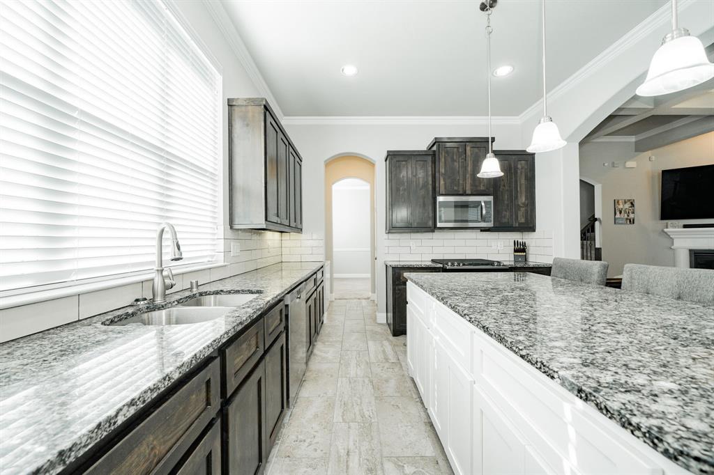 593 Spruce Trail Forney, TX 75126 - Photo 11 of 40 Kitchen with arched walkways, dark stone counters, hanging light fixtures, stainless steel appliances, and tasteful backsplash