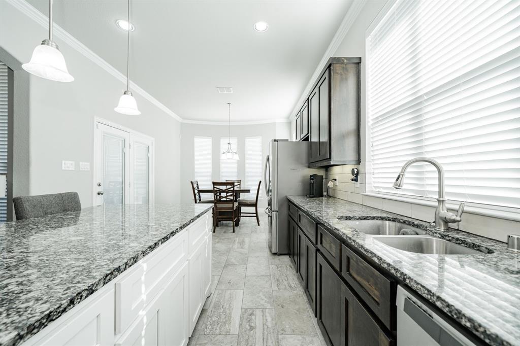 593 Spruce Trail Forney, TX 75126 - Photo 12 of 40 Kitchen featuring dark stone counters, decorative light fixtures, crown molding, stainless steel dishwasher, and recessed lighting