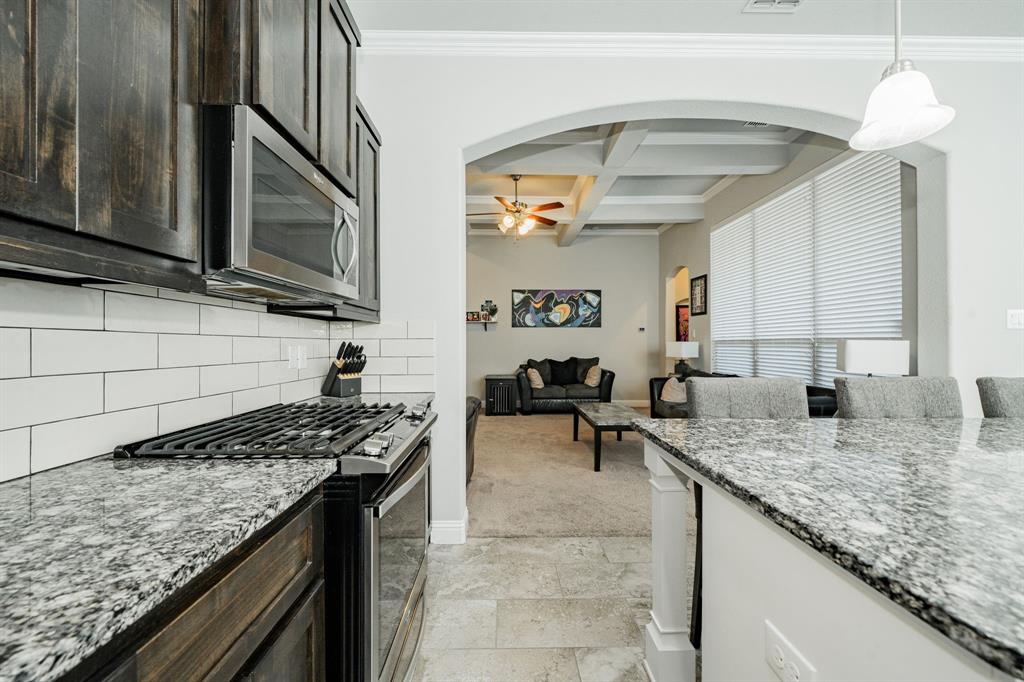 593 Spruce Trail Forney, TX 75126 - Photo 13 of 40 Kitchen with light stone counters, coffered ceiling, appliances with stainless steel finishes, beamed ceiling, and hanging light fixtures