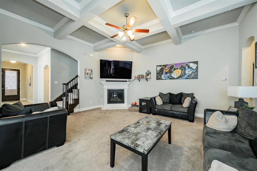 593 Spruce Trail Forney, TX 75126 - Photo 4 of 40 Living area with arched walkways, ornamental molding, carpet, coffered ceiling, and a glass covered fireplace
