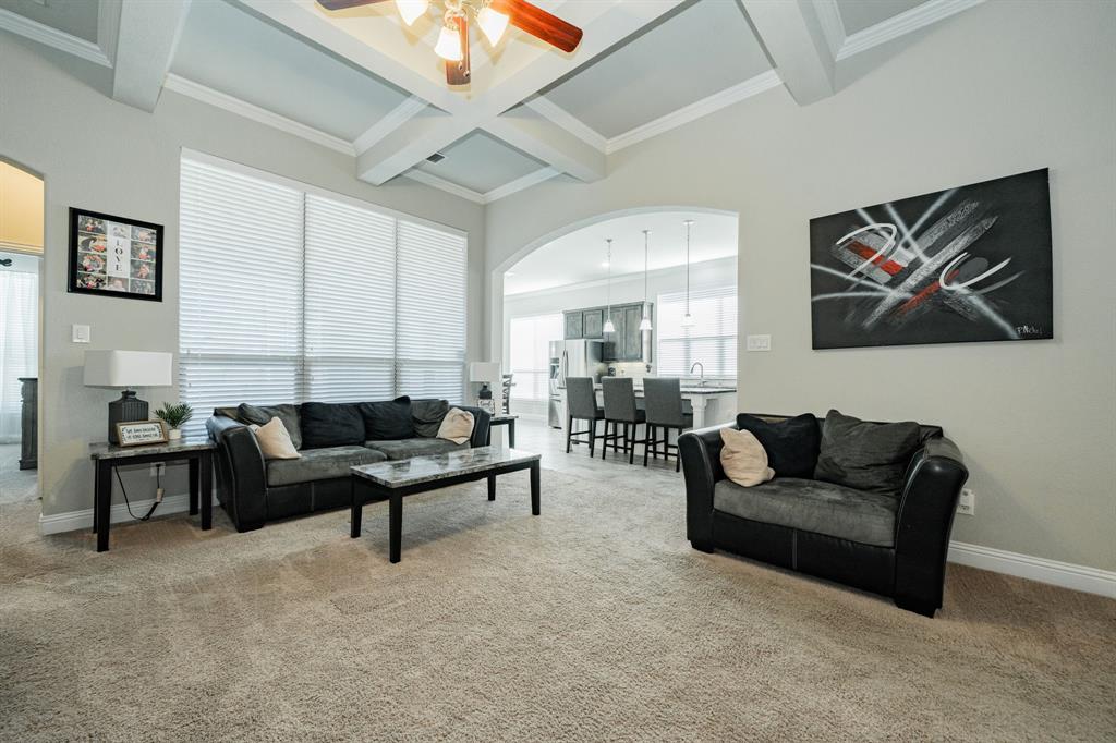 593 Spruce Trail Forney, TX 75126 - Photo 7 of 40 Living room with arched walkways, beamed ceiling, coffered ceiling, light colored carpet, and crown molding