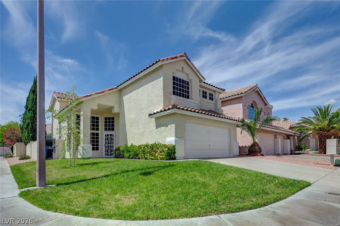 This residence features a stucco exterior, tile roof, and an attached garage with a paved driveway.