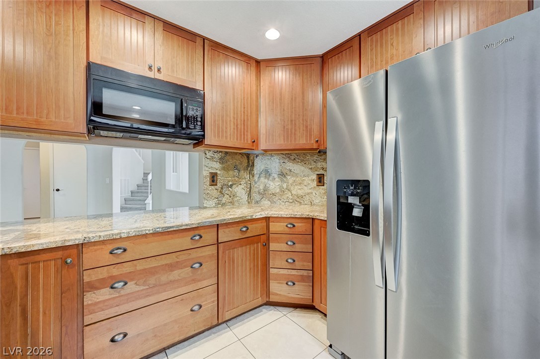 9301 Magic Flower Avenue Las Vegas, NV 89134 - Photo 32 of 70 This modern kitchen features warm wood cabinetry and granite countertops, creating a welcoming and functional space.