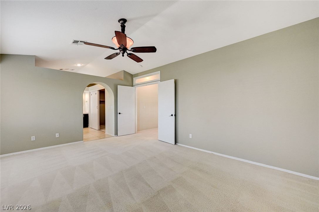9301 Magic Flower Avenue Las Vegas, NV 89134 - Photo 45 of 70 This primary bedroom offers plush carpet flooring, a ceiling fan, and convenient access to the primary bathroom.