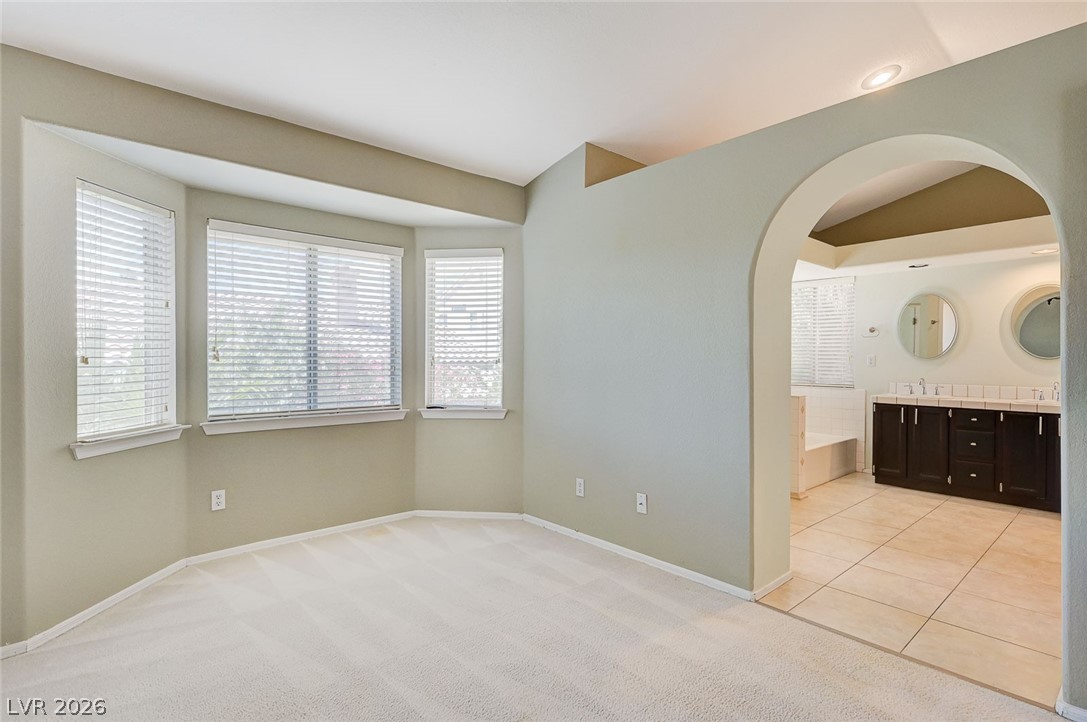 9301 Magic Flower Avenue Las Vegas, NV 89134 - Photo 47 of 70 This spacious primary suite features a cozy carpeted area leading to a bright bathroom with tile flooring.