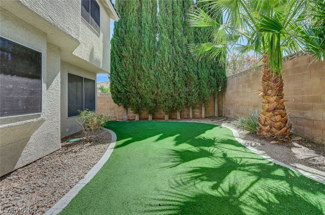 9301 Magic Flower Avenue Las Vegas, NV 89134 - Photo 67 of 70 This private yard offers lush turf and mature greenery, perfect for serene outdoor living.