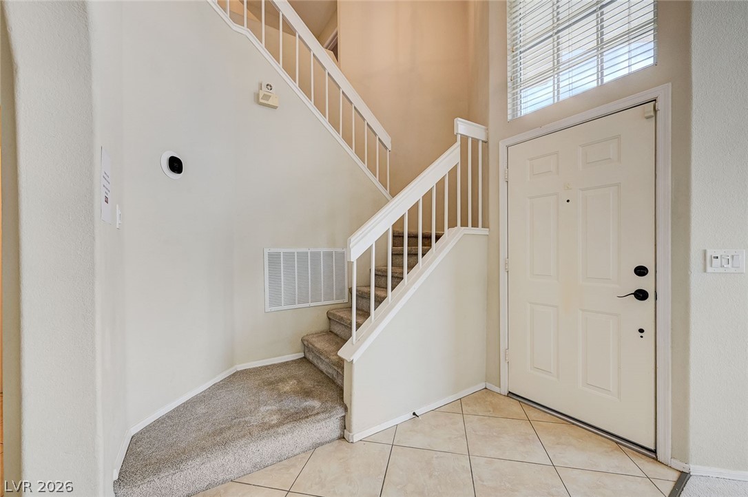 9301 Magic Flower Avenue Las Vegas, NV 89134 - Photo 9 of 70 This inviting entry features a carpeted staircase, leading to the home's upper level, with tiled flooring.