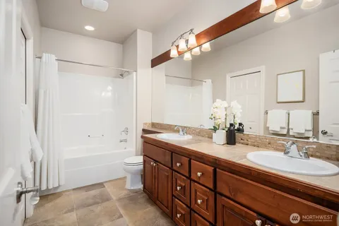 a bathroom with a granite countertop sink a toilet a large mirror and shower