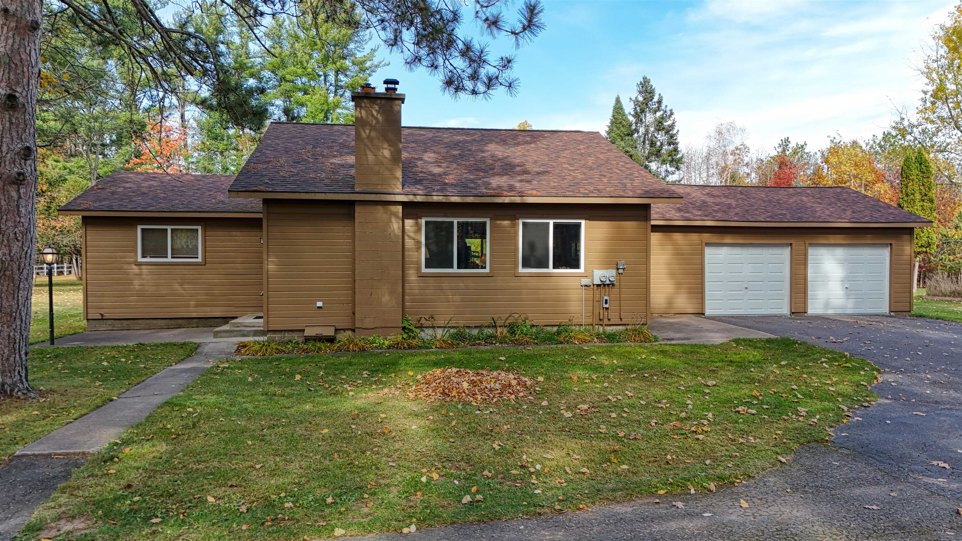 View of front of property featuring a chimney, a front lawn, roof with shingles, and an attached garage