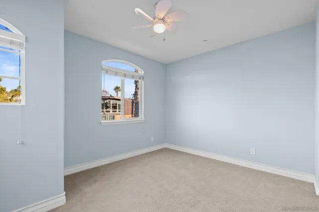 an empty room with a window and ceiling fan