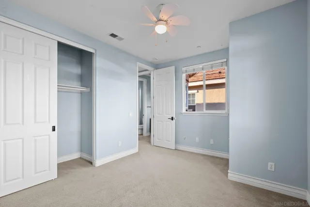 an empty room with closet and a ceiling fan