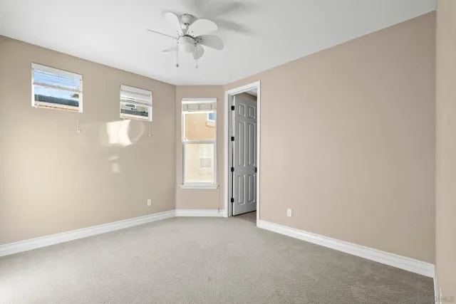 an empty room with windows and fan