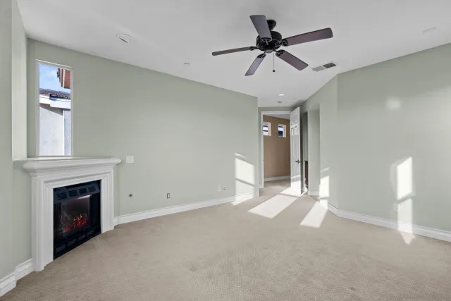 a view of an empty room with chandelier fan and fire place