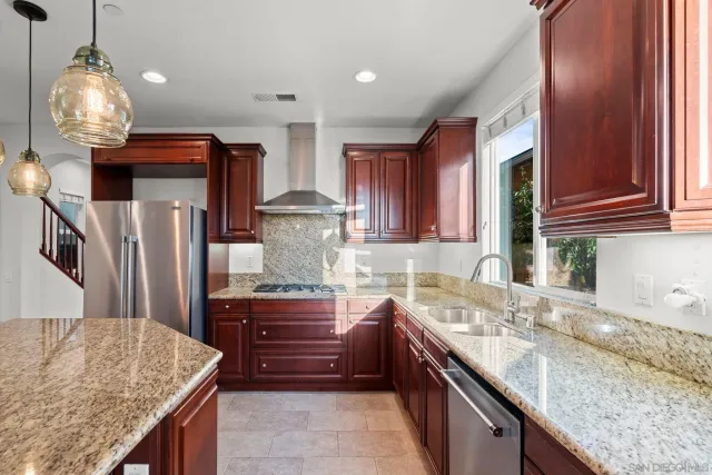 a kitchen with granite countertop a sink a counter top space and stainless steel appliances