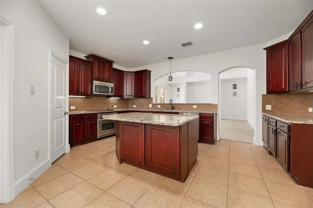 a kitchen with kitchen island granite countertop a sink stove top oven and wooden cabinets