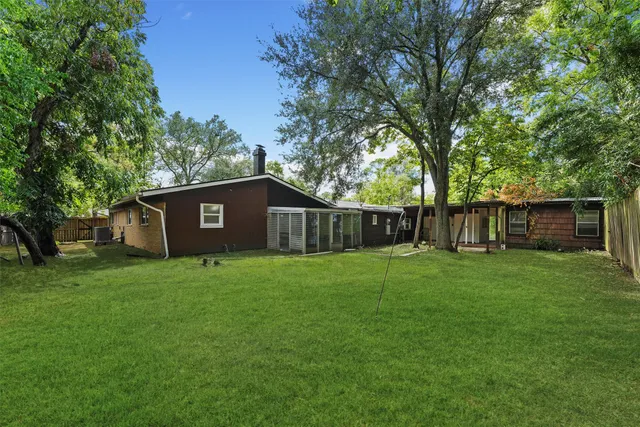 a view of a backyard with large trees and wooden fence