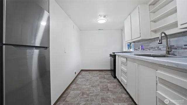 a kitchen with stainless steel appliances a stove and white cabinets