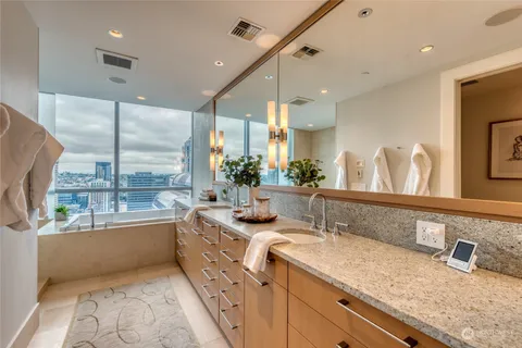 a bathroom with a granite countertop tub a double vanity sink and a large mirror