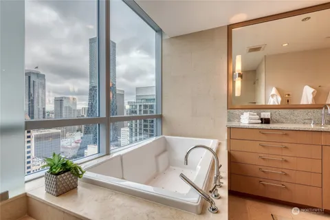 a bathroom with a granite countertop sink a toilet a mirror and tub