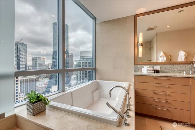 a bathroom with a granite countertop sink a toilet a mirror and tub